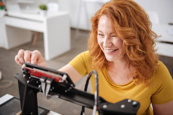 Веселая позитивная женщина смотрит на монитор 3D принтера — стоковое фото