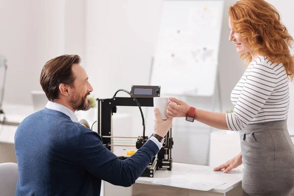 Deliziosa donna amichevole dando al suo collega una tazza di caffè — Foto Stock