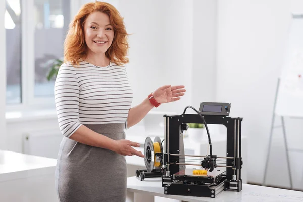 Goed uitziende aantrekkelijke vrouw toont u een 3D-printer — Stockfoto