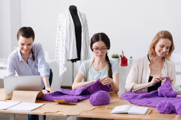 Female atelier tailors knitting scarves
