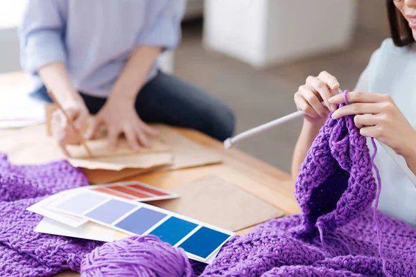 Mani femminili che lavorano a maglia un cappello viola — Foto Stock