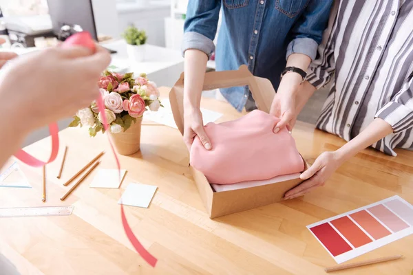 Női kezek csomagolás egy ruha, egy doboz — Stock Fotó