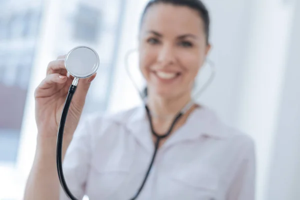 Delightful practitioner demonstrating stethoscope in the hospital — Stock Photo, Image