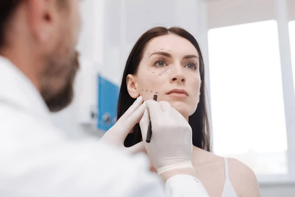 Praktische produktive plastische Chirurg zeichnet Richtlinien auf Patienten Gesicht — Stockfoto