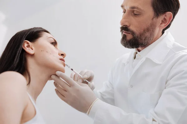 Delicate scrupulous plastic surgeon performing lip augmentation — Stock Photo, Image