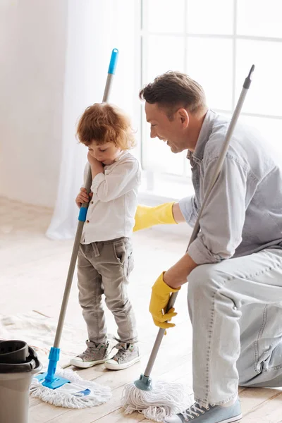 Vertical photo of father and son while holding mops — Stock Photo, Image