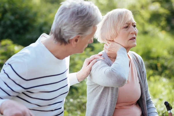 Distracted pensioner feeling terrible pain in the neck outdoors — Stock Image Distracted pensioner feeling terrible pain in the neck outdoors Royalty Free Stock Photos