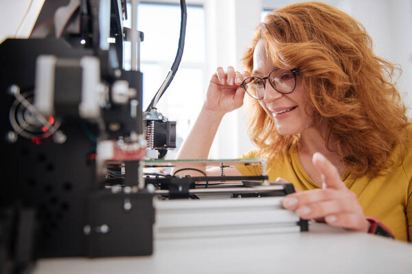 Nice pleasant woman looking at the 3d printer details Royalty Free Stock Images