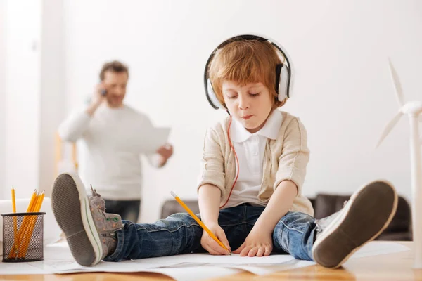 Niño serio escuchando música mientras está sentado en la mesa — Foto de Stock