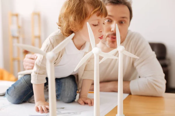 Lustiger Vater bläst auf Windmühlenmodelle — Stockfoto