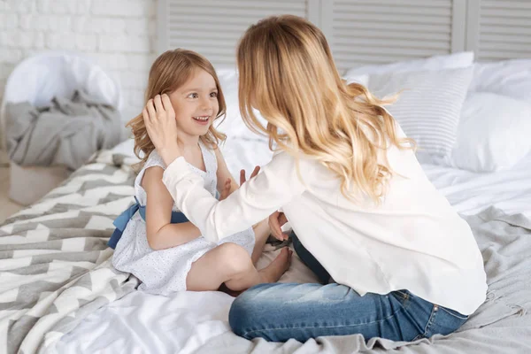 Jeune mère blonde touchant les cheveux de ses filles — Photo