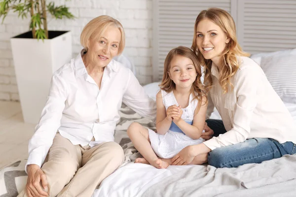 Three generations of women sitting on one bed — Stock Photo, Image
