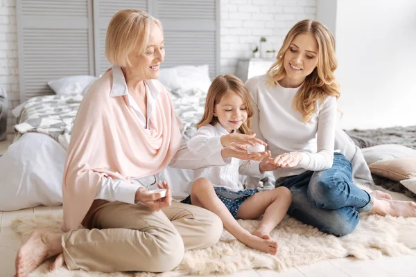 Grandmother holding a cream jar for her granddaughter and daughter — Stock Photo, Image