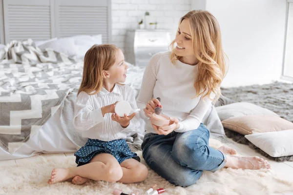 Jovem mãe e sua filha discutindo cosméticos — Fotografia de Stock