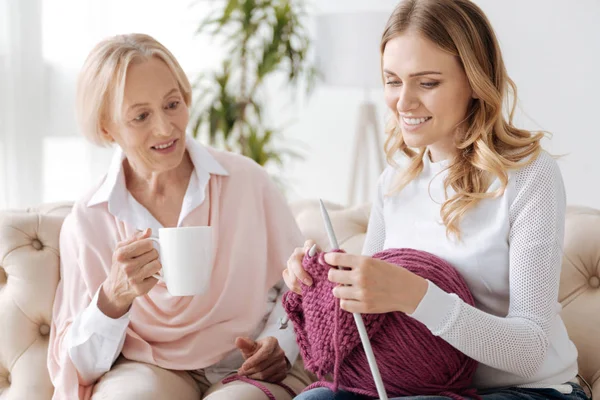 Senior mother watching her daughter knitting — Stock Photo, Image