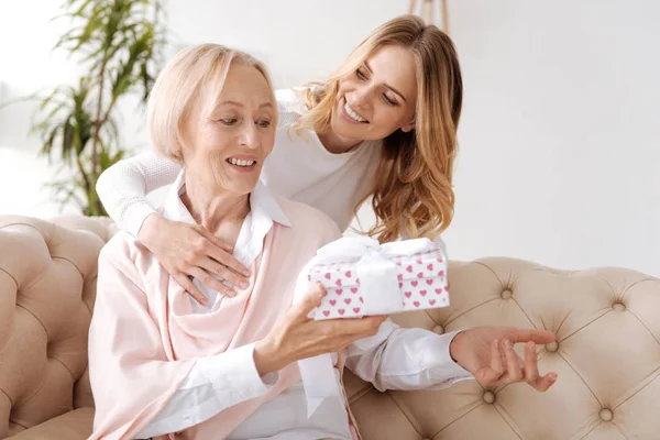 Hinreißende junge Frau schenkt ihrer Mutter ein Geschenk — Stockfoto