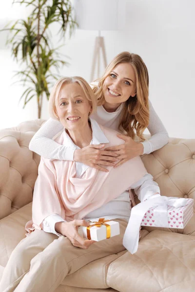 Figlia abbracciando madre holding presenta — Foto Stock