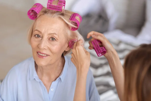 Mains féminines aidant à mettre sur les rouleaux de cheveux — Photo