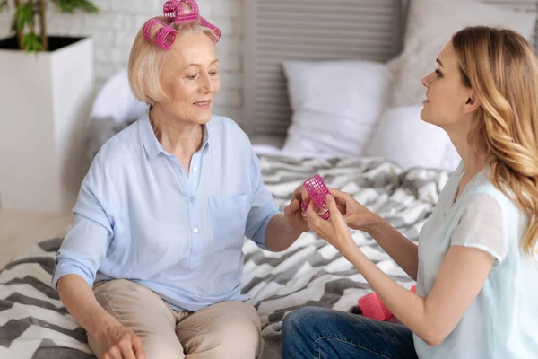 Señora mayor tomando un rodillo de pelo de sus hijas manos — Foto de Stock