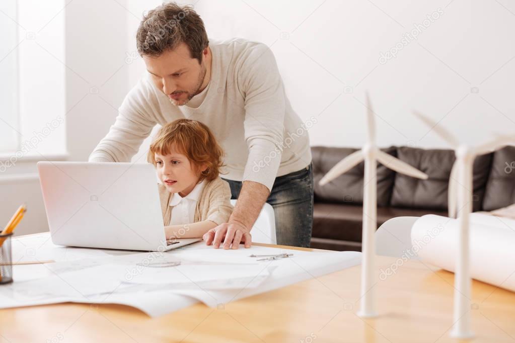 Serious father looking at screen of computer