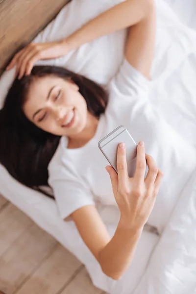 Donna che tiene smartphone a letto — Foto Stock