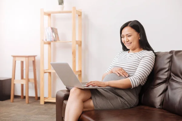 Усміхнена вагітна жінка використовує ноутбук — стокове фото