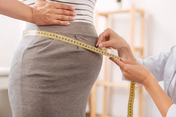 Nice woman measuring belly of her client — Stock Photo, Image