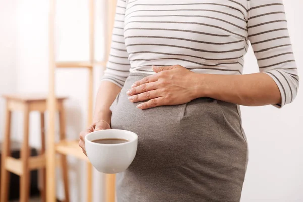 Plerasant mulher grávida segurando uma xícara de café — Fotografia de Stock
