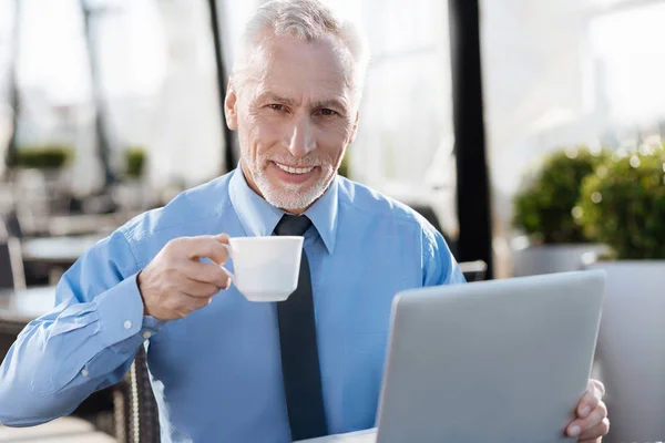 Senior man positiviteit uiten terwijl het drinken van koffie — Stockfoto