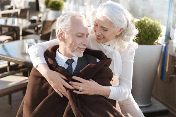 Tender woman covering her partner with plaid — Stock Photo, Image