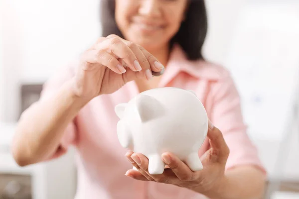 Positieve vrouw munten ingebruikneming een piggy bank — Stockfoto