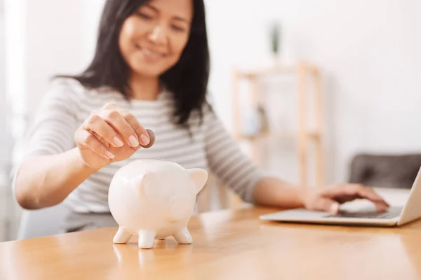 Positieve vrouw munten ingebruikneming piggy bank — Stockfoto