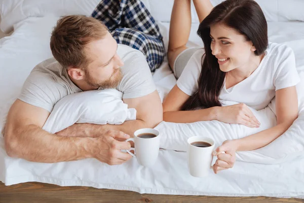 Ζευγάρι, διατηρώντας επαφή με τα μάτια, ενώ χαλαρώνετε στο κρεβάτι με τον καφέ — Φωτογραφία Αρχείου