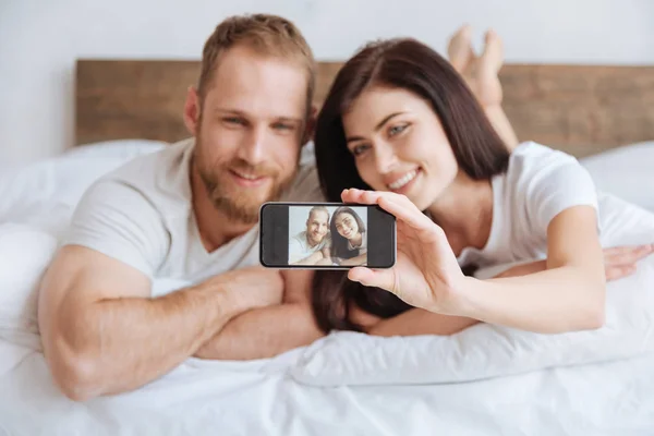 Porträtt av nygifta paret tar selfie i sängen — Stockfoto