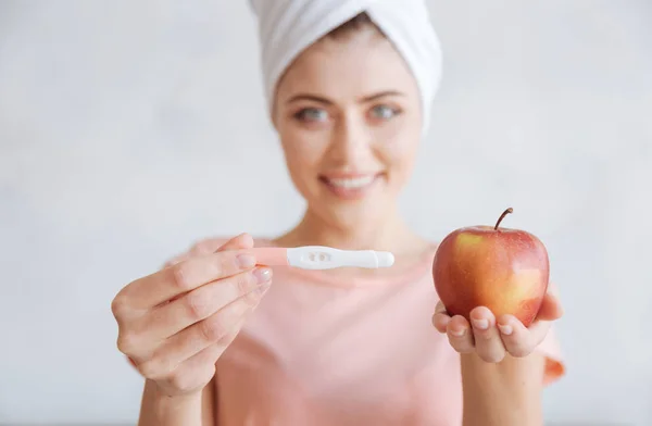 Retrato de mulher segurando teste de gravidez e maçã — Fotografia de Stock