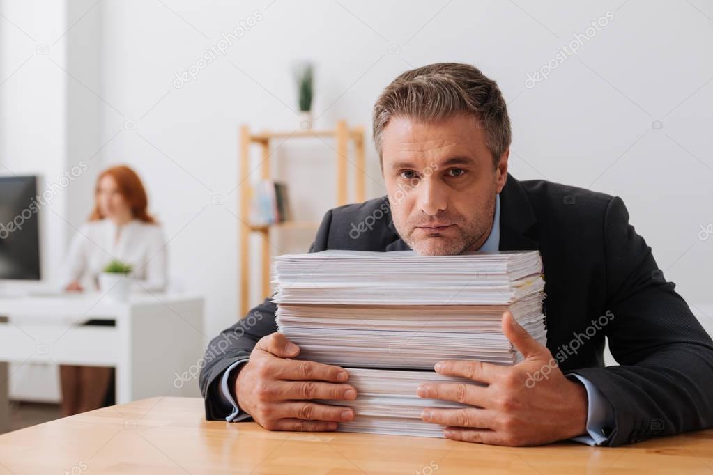 Persistent talented employee receiving a lot of papers working with