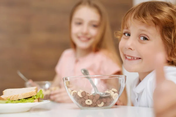 Fröhliches, ausdrucksstarkes Kind, das sein Frühstück liebt — Stockfoto