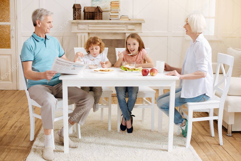 Charming excited children enjoying breakfast with their grandparents