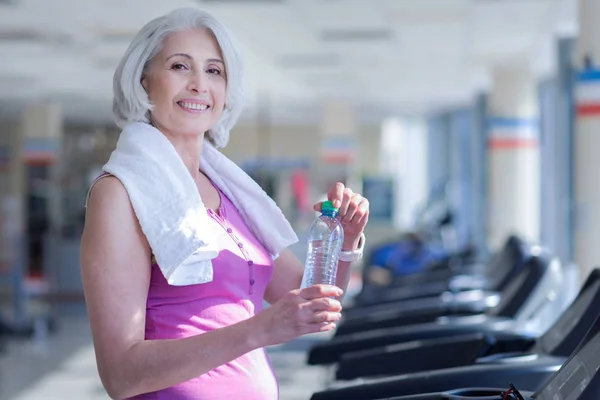 Woman with towel and water at gym — Stock Photo, Image