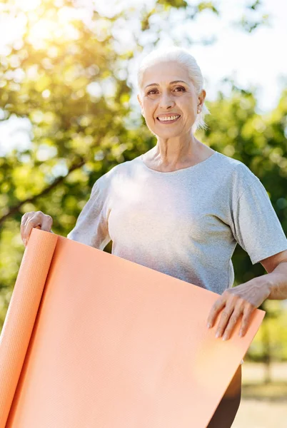 Idős nő gazdaság jóga szőnyeg — Stock Fotó