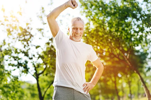 Веселый пенсионер, занимающийся спортивными упражнениями в парке — стоковое фото