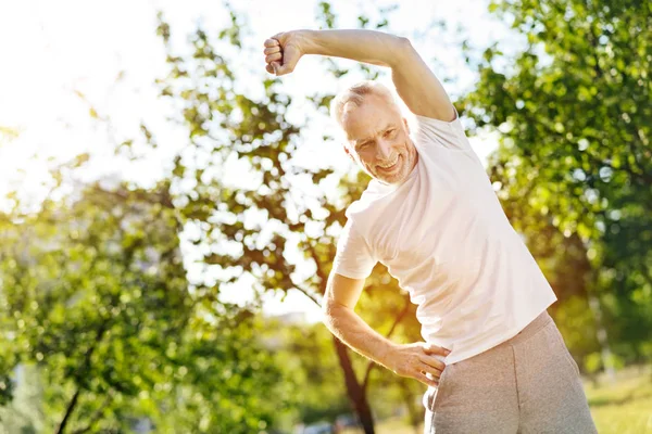 Позитивный пожилой человек делает упражнения на растяжку — стоковое фото