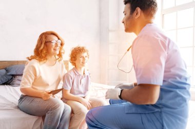 Yatakta onun anne yakın oturan boy gülümseyerek