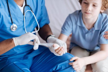 Hayal kırıklığına uğramış çocuk doktoru dizlerinin üzerine elini koyarak