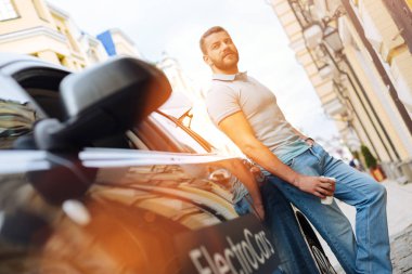 Yakışıklı adam onun yeni elektrikli otomobil poz