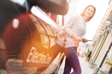 Sevimli kadın arabası üzerinde tablet tutarken yaslanmış