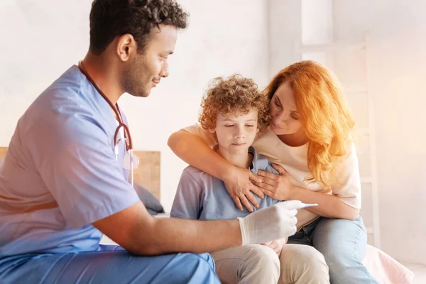 Amable madre abrazando a su hijo mientras visita al médico — Foto de Stock