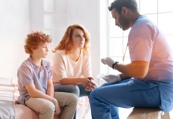 Atento madre cruzando los dedos mientras escucha a su médico — Foto de Stock