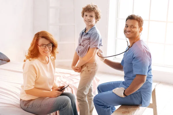 Positivo ragazzo felice in piedi tra il suo medico e la mamma — Foto Stock