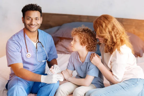 Trabalhador médico encantado positivo que trata a mão ferida — Fotografia de Stock